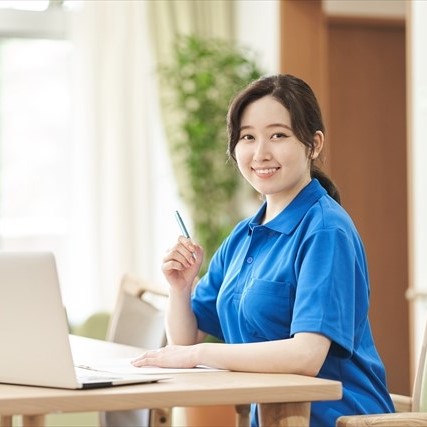 青い作業着を着てパソコンを触る女性