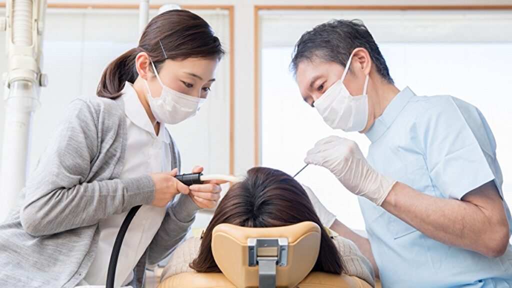 歯の治療を行う歯科医と助手