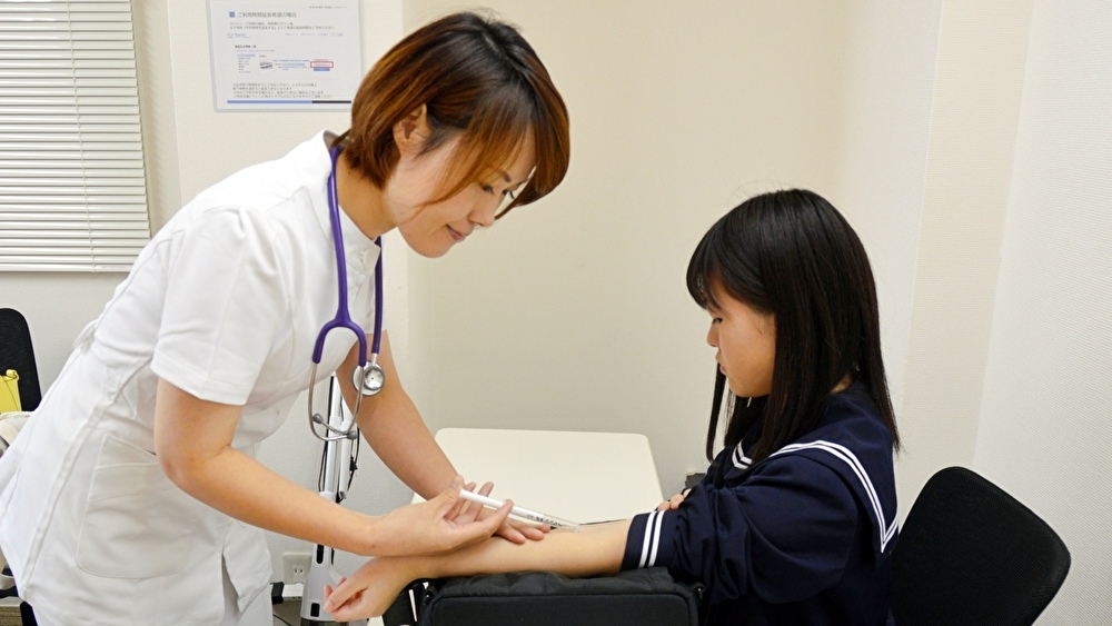 女子中学生に注射する看護師