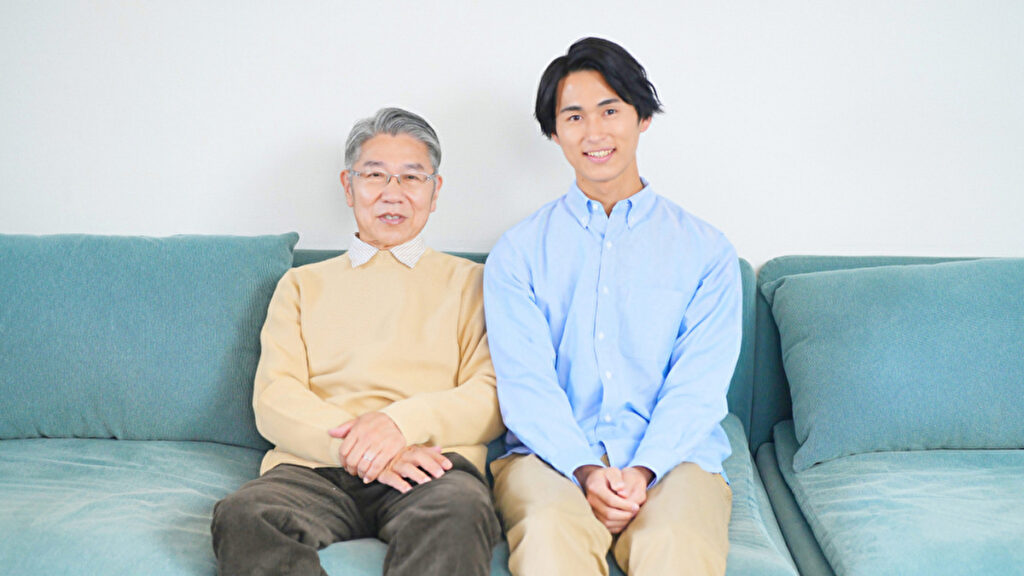 ソファーに腰掛ける年配の男性とその息子