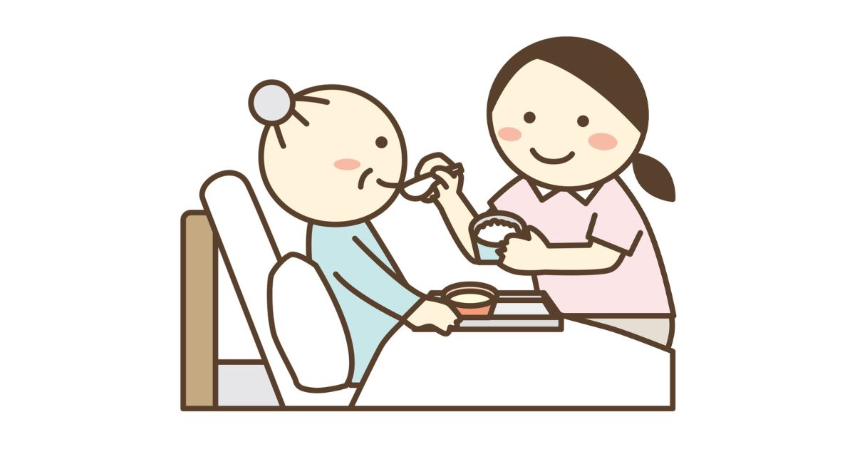 介護ベッドに横たわるお年寄りに食事を食べさせる女性