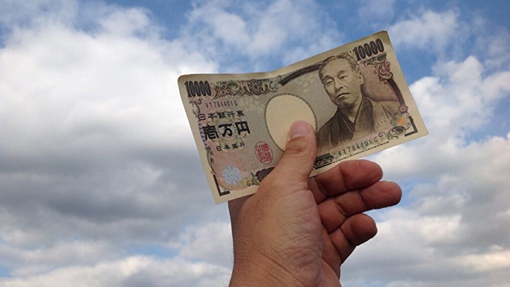 一万円札を空に向けている手