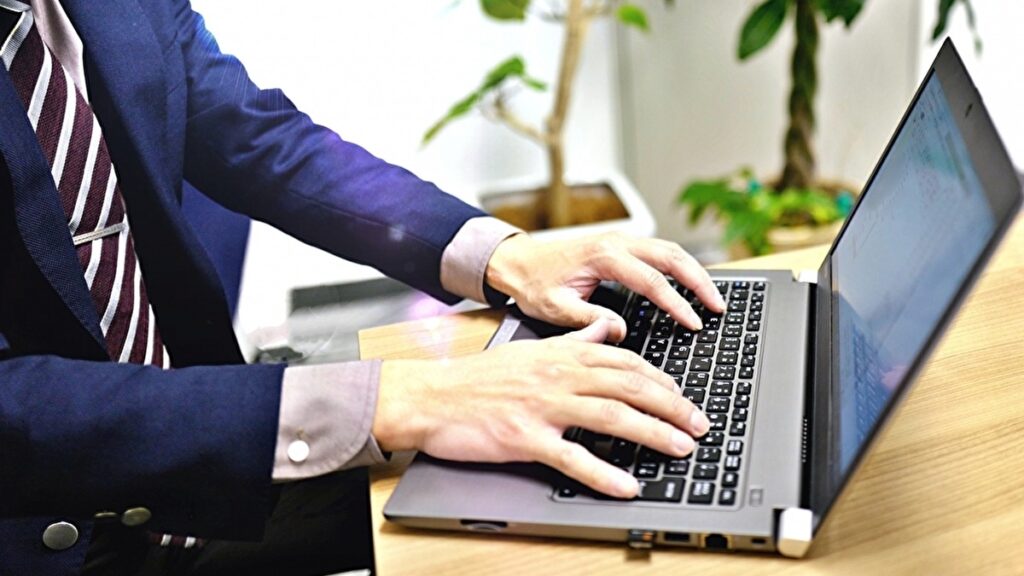 パソコンを操作するスーツを着た男性の手