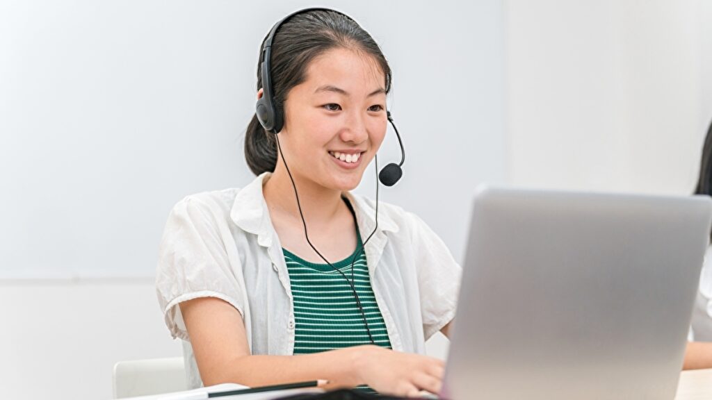 ヘッドセットを付けてパソコンの前で英会話の勉強をする女性