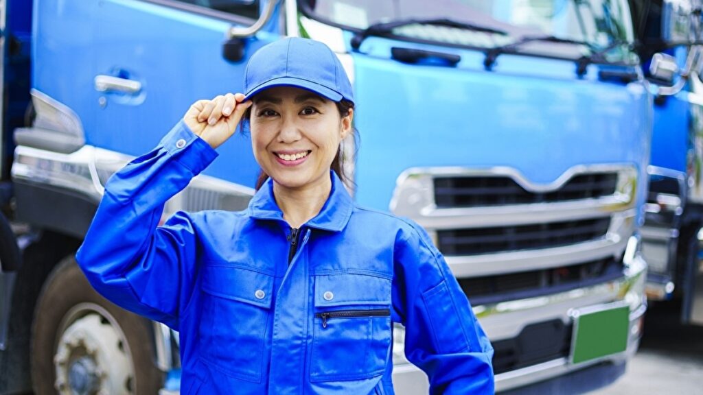 青い作業着を着た女性トラックドライバー