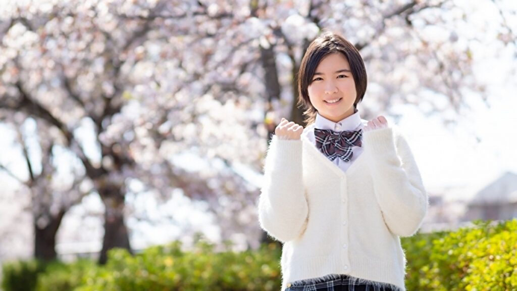 桜の木の下でガッツポーズをする女子高校生