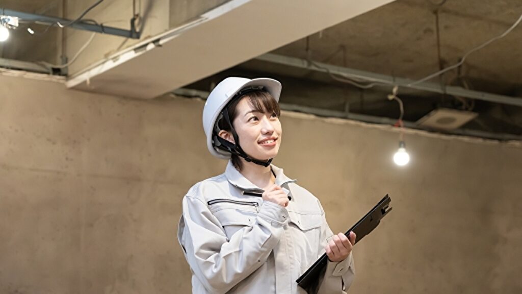 コンクリート製の天井を点検するヘルメットをかぶった女性