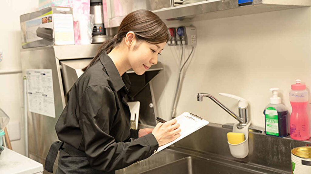 飲食店の厨房で衛生状態をチェックする女性