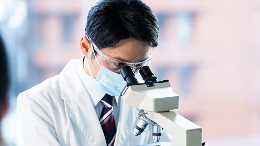 顕微鏡を覗き込む白衣の男性