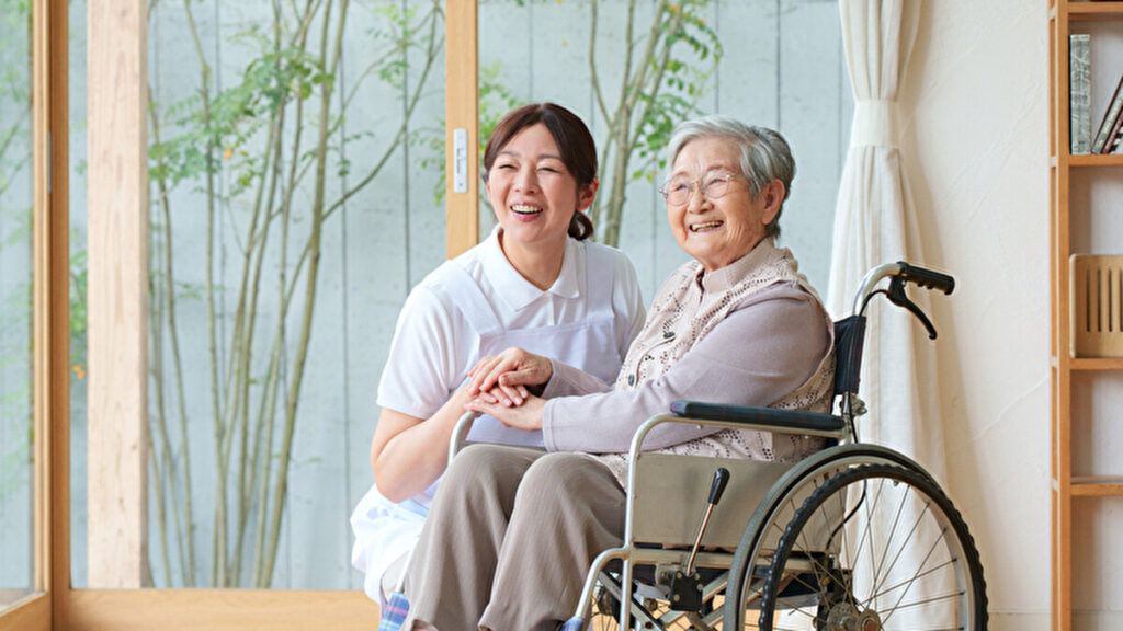車椅子のお年寄りを介護する女性