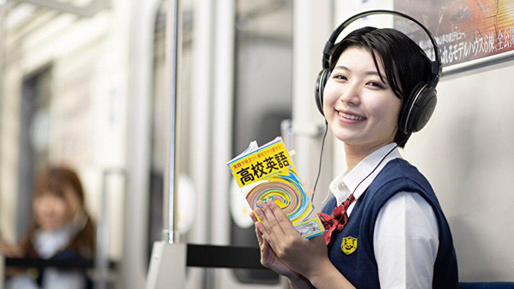 電車の中で英語のリスニングをする女子高生
