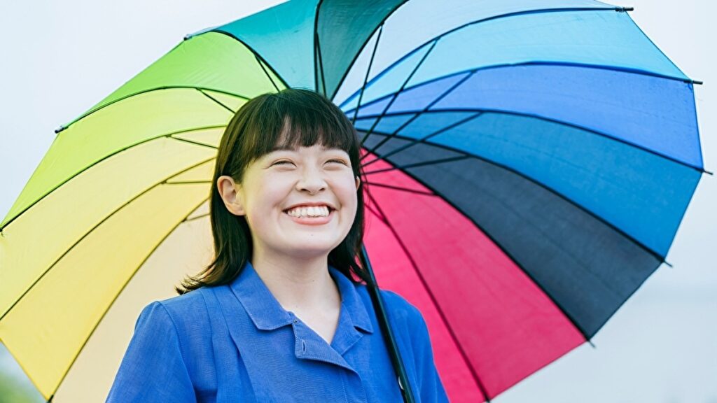 カラフルな傘をさす笑顔の女性